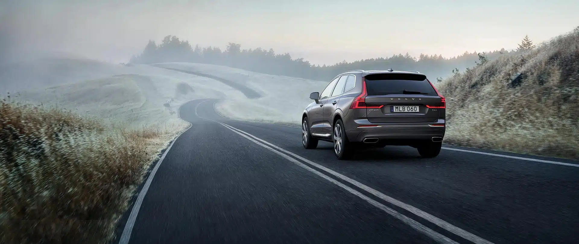 Mörkgrön Volvo XC60 Recharge körandes på dimmig landsväg